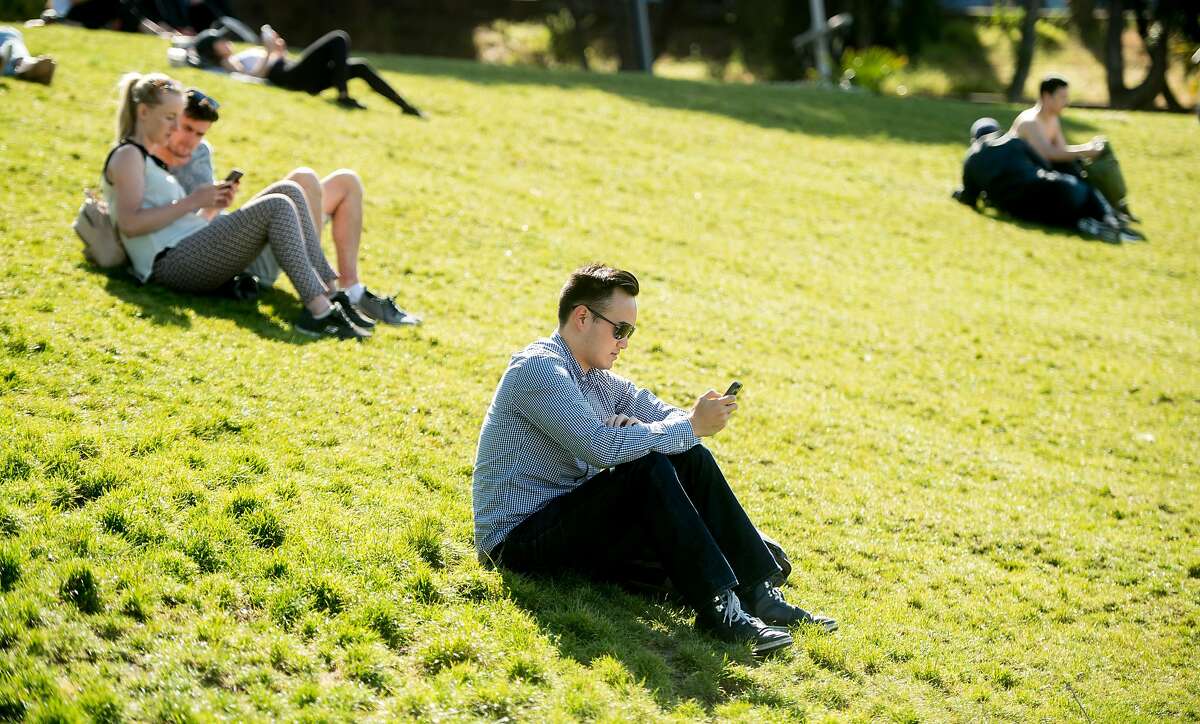 Patrick Ngo and other Mission Dolores Park visitors use cell phones on Monday, June 5, 2017. The park offers a free San Francisco WiFi hotspot.