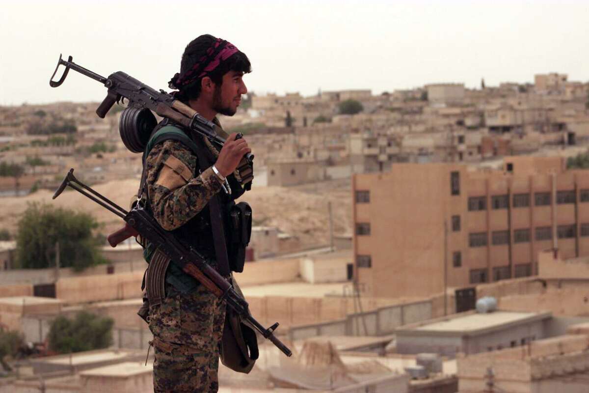 FILE - In this Sunday, April 30, 2017, file photo, provided by the Syria Democratic Forces (SDF), shows a fighter from the SDF carrying weapons as he looks toward the northern town of Tabqa, Syria. A U.S. military official says the offensive against the Islamic State group's de facto capital, Raqqa "will be long and difficult." Lt. Gen. Steve Townsend, the top U.S. commander in Iraq, says the assault by the Syrian Democratic Forces will deliver a decisive blow to the idea of IS "as a physical caliphate." The Kurdish-led force launched an offensive to capture Raqqa on Tuesday.(Syrian Democratic Forces, via AP, File)