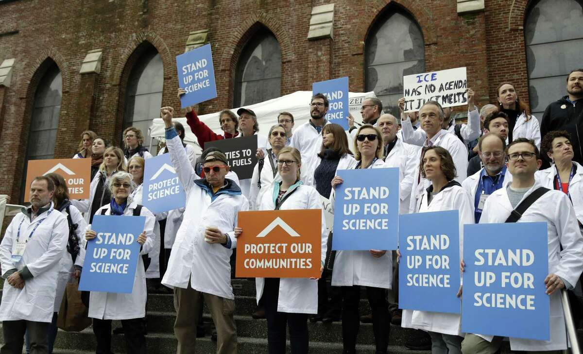 FILE - In this Dec. 13, 2016 file photo, scientists hold signs during a rally in conjunction with the American Geophysical Union's fall meeting in San Francisco. The rally was to call attention to what scientist believe is unwarranted attacks by the incoming Trump administration against scientists advocating for the issue of climate change and its impact. Vowing to keep the United States on track to meet its emissions-cutting target even without the U.S. government's support, more than a dozen governors representing nearly 40 percent of the U.S. economy by Tuesday, June 6, 2017, had pledged themselves to stay in the climate-change fight despite the Trump administration's withdrawal from the Paris climate accords last week. (AP Photo/Marcio Jose Sanchez, File)
