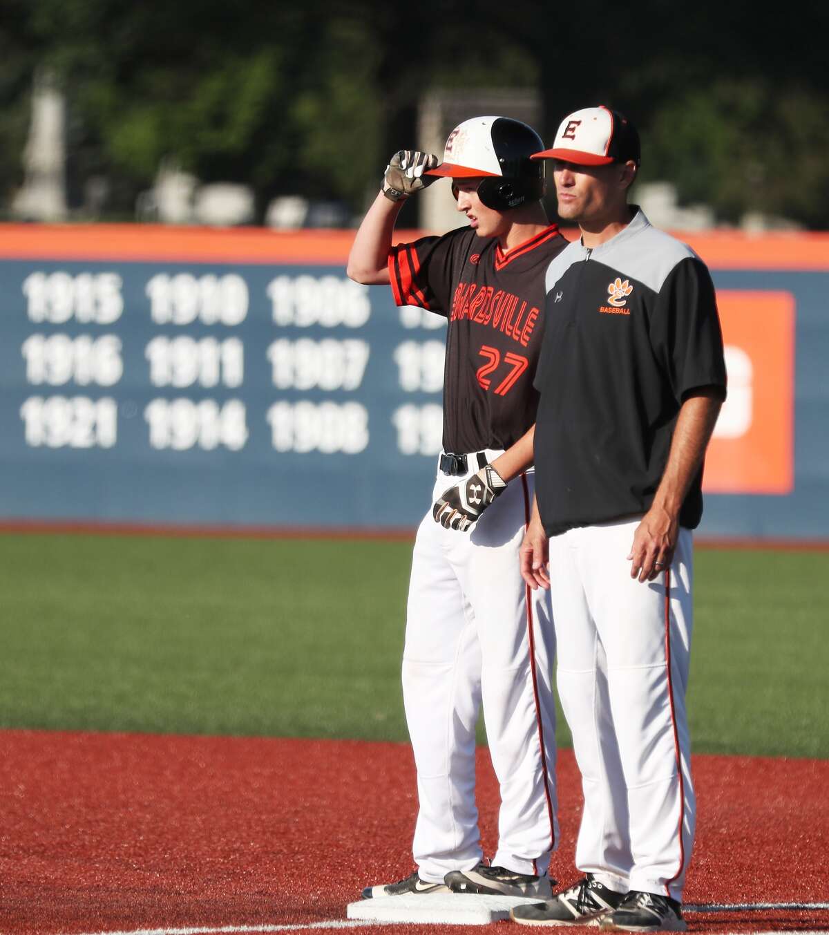 Edwardsville’s Cole Hampton, left, stands at first base after an RBI single. Assistant coach Craig Ohlau stands by his side.