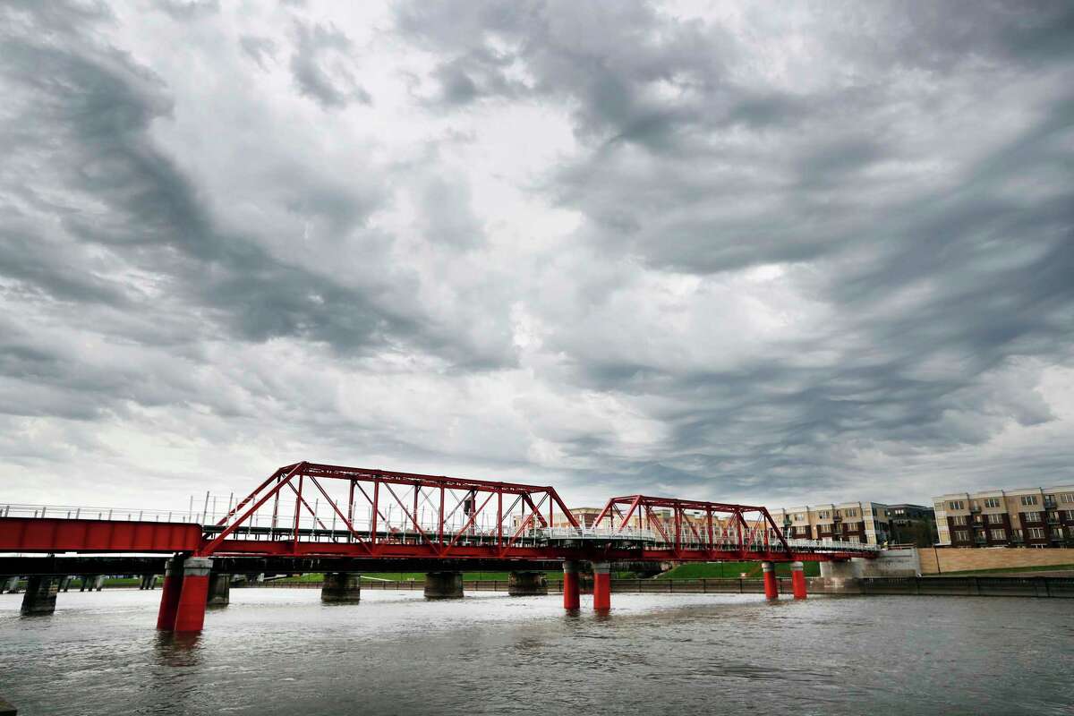 In this April 18, 2017, photo, the Red Bridge pedestrian bridge is seen over the Des Moines River in Des Moines, Iowa. A little more than a decade after it was restored, crews went back to the site with a crane to hoist the span more than 4 feet higher, at a cost of $3 million, after experts concluded that the river's flooding risk was double the previous estimates. (AP Photo/Charlie Neibergall)