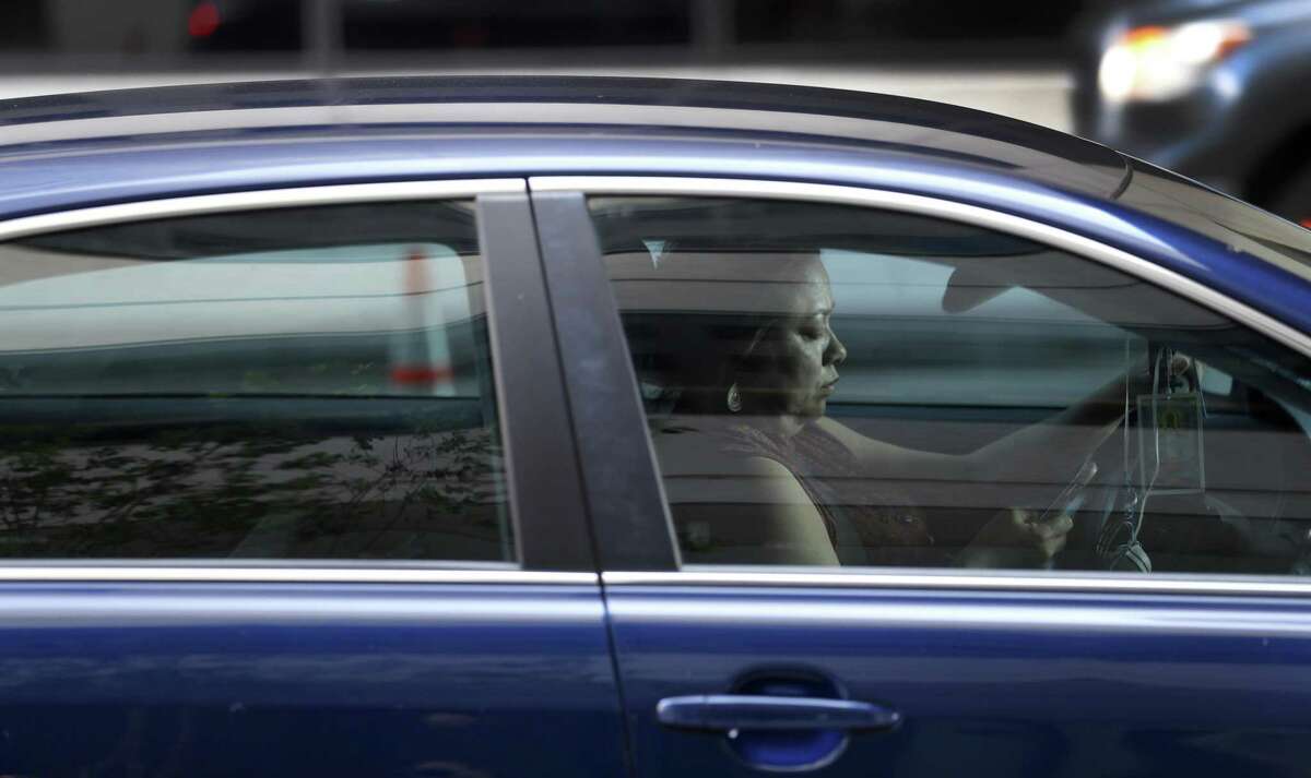 A Houston driver checks messages on her cellphone as she waits for a red light.