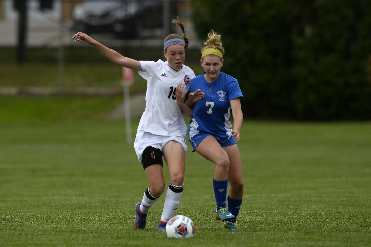 Grand Blanc's Kennedy High, left, and Midland High's Madison Schwind fight for possession of the ball in the first half of the Division 1 regional soccer game against Grand Blanc High School Tuesday evening. Grand Blanc defeated Midland 4-0.