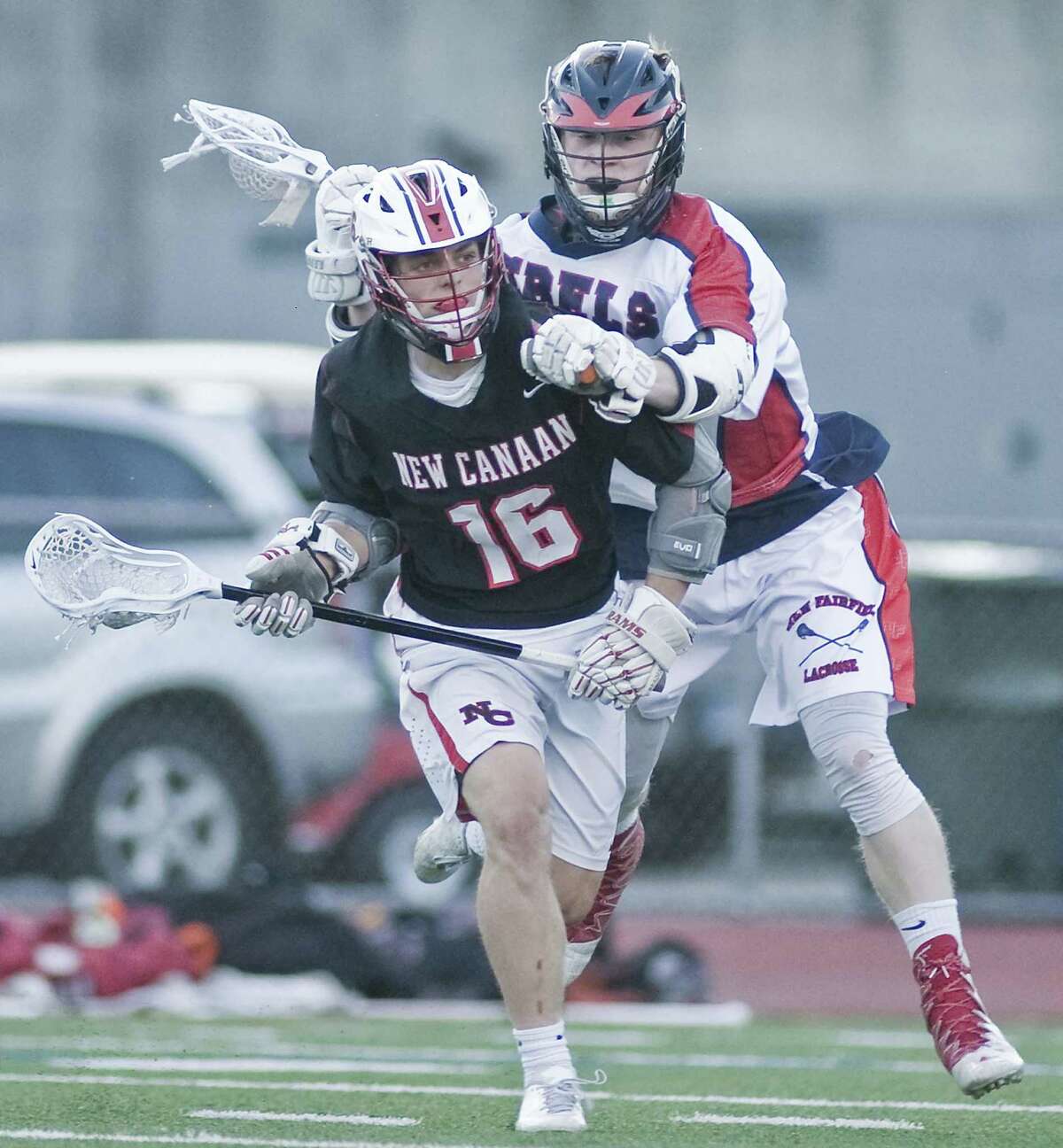 NEW CANAAN 21, NEW FAIRFIELD 6: New Canaan’s Graham Braden takes a hit from New Fairfield’s Colin Ford in the Class M boys lacrosse semifinal Wednesday at Brien McMahon High School in Norwalk