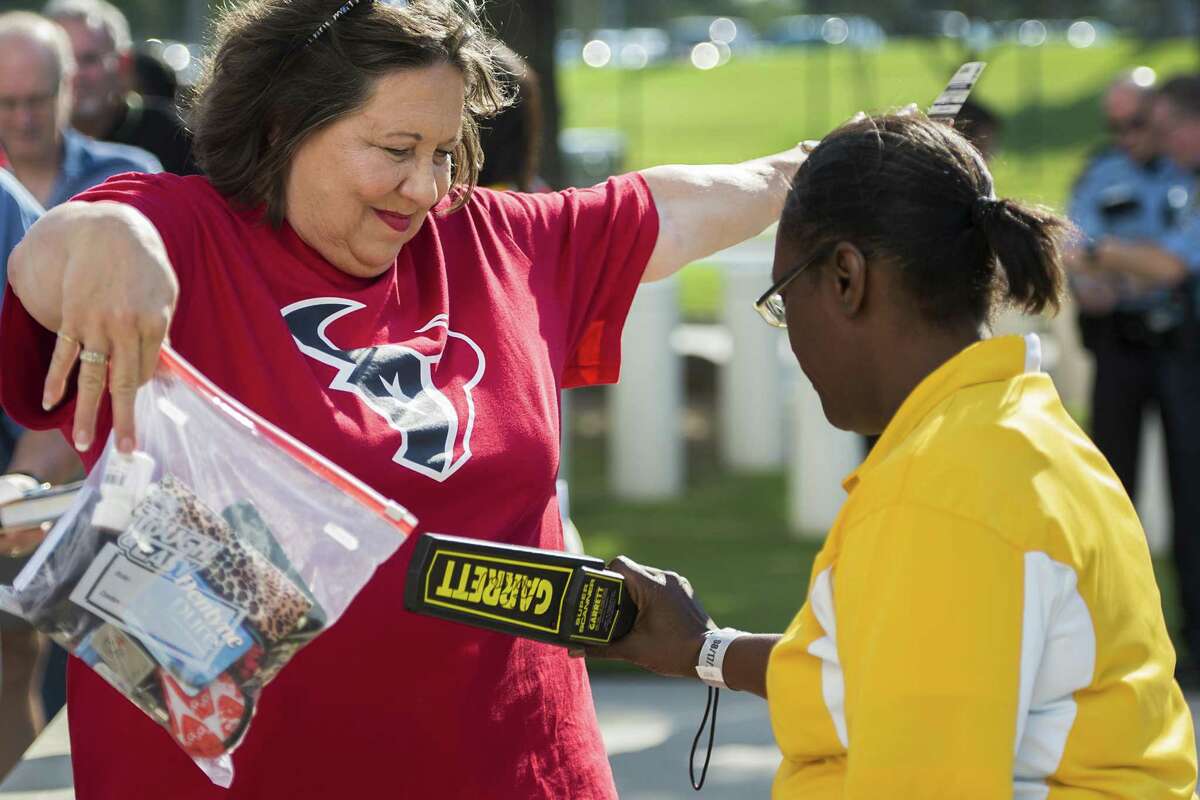 Houston Texans fan Regina Brower holds up a clear bag with her belongings as she goes through security screening at Reliant Stadium on Aug. 17, 2013, in Houston. The Alamodome is instituting a policy similar to one the National Football League has in place at stadiums.