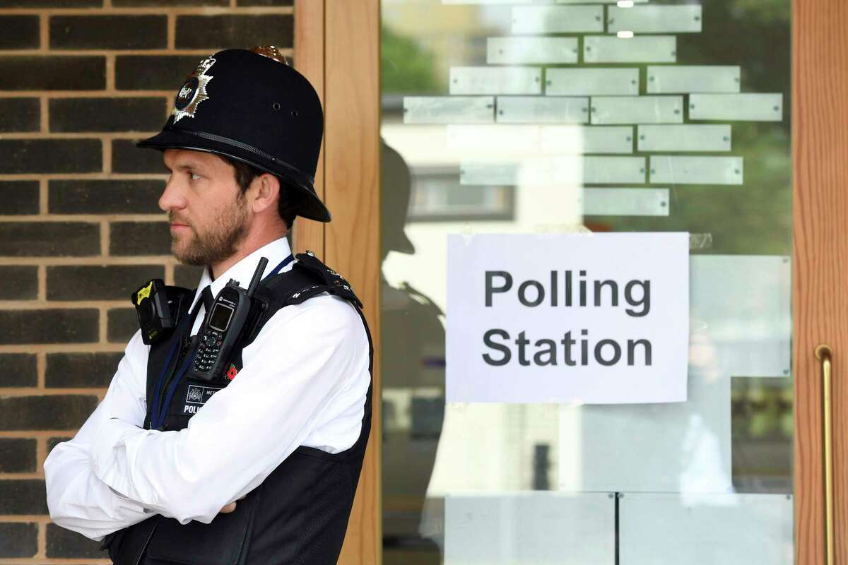 A police officer is stationed outside a polling station at Cubitt Town Infant and Junior School on the Isle of Dogs in London, as people cast their votes in the general election, Thursday June 8, 2017. (Victoria Jones/PA via AP)