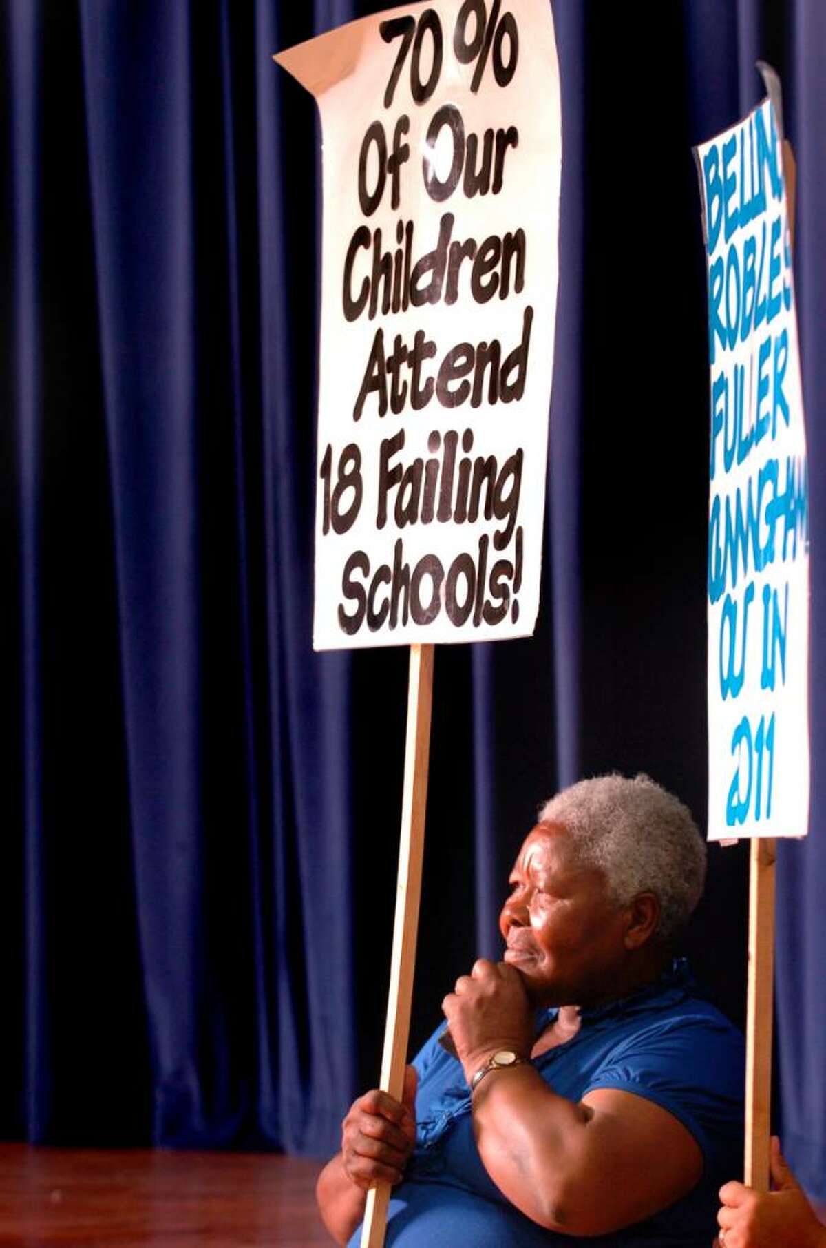 Community member Emeline Bravo-Blackwood holds a sign as she listens to Superintendent of Schools John Ramos answer questions from parents Tuesday June 8, 2010 during a meeting to discuss plans to close Roosevelt School as part of a budget cutting measure.