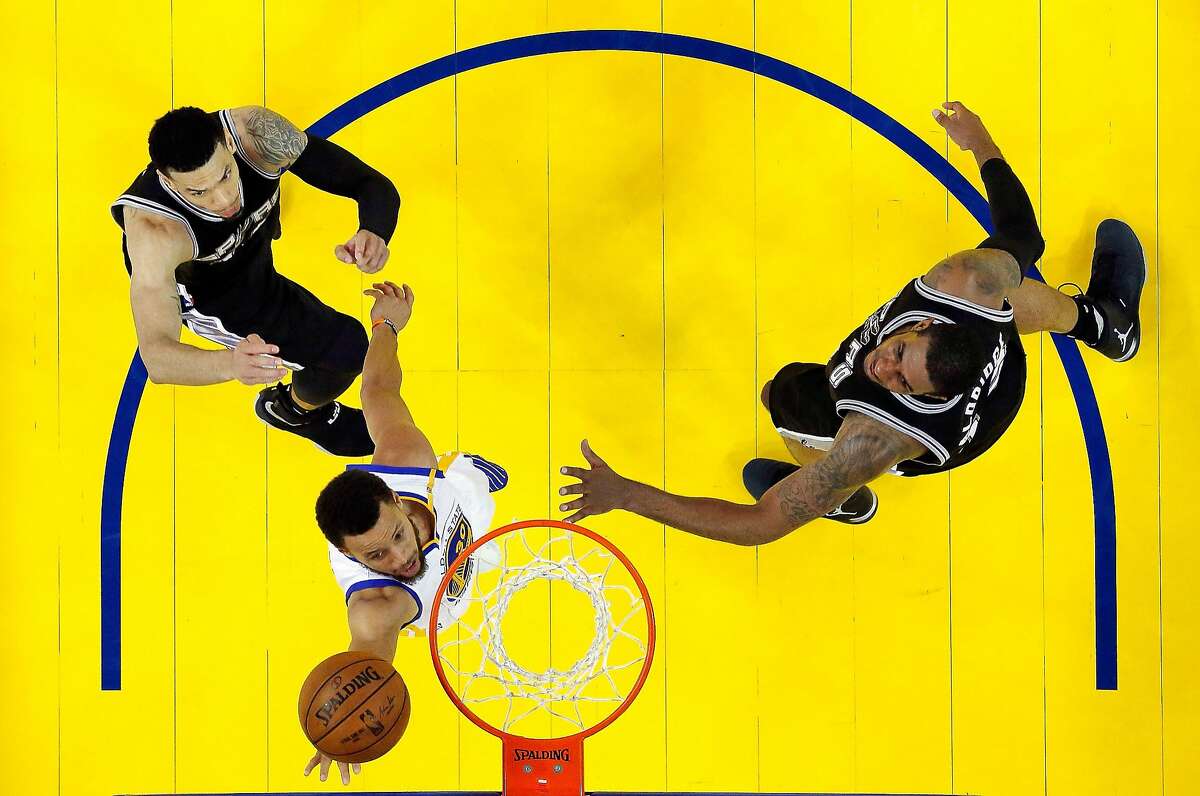 Stephen Curry (30) slips past LaMarcus Aldridge (12) and Danny Green (14) for a layup in the second half as the Golden State Warriors played the San Antonio Spurs at Oracle Arena in Oakland, Calif., on Sunday, May 14, 2017, in Game 1 of the 2017 Western Conference Finals. The Warriors defeated the 113-111.