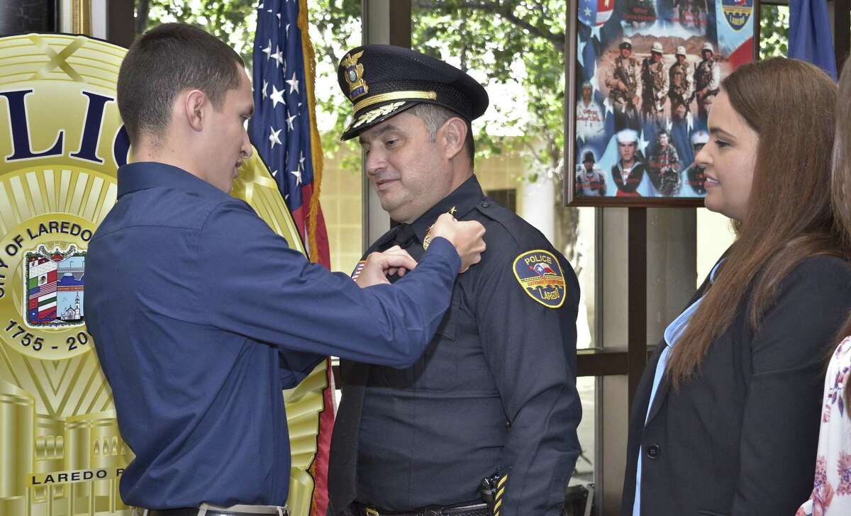 Claudio Treviño III places the LPD chief badge on his father, Claudio Treviño Jr., during the swearing-in ceremony Thursday at LPD headquarters.