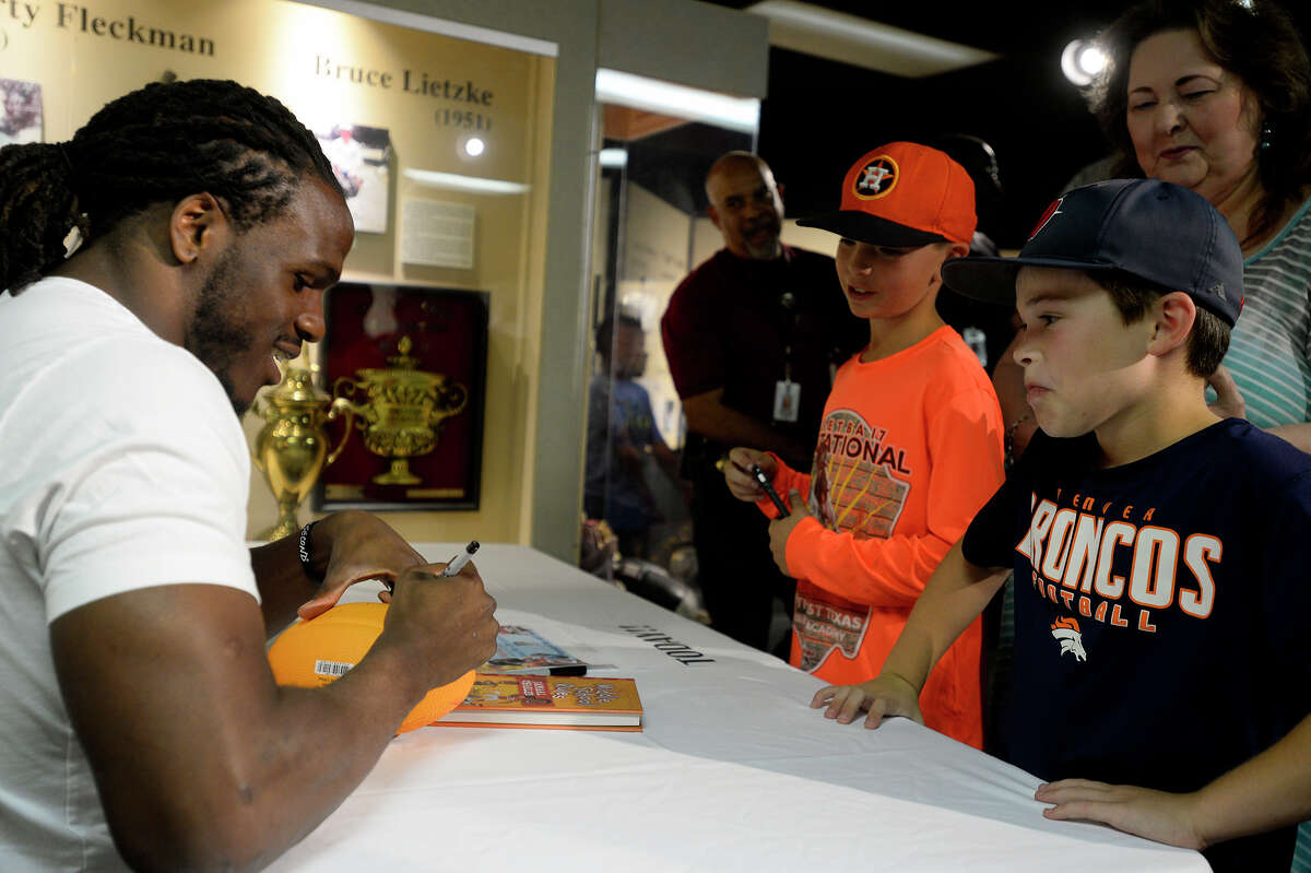 Jamaal Charles, a Port Arthur native who plays for the Denver Broncos, signs a football for Eli Curtis, 9, and CJ Swanzy, 9, at the Museum of the Gulf Coast on Friday. Charles was at the museum to sign copies of his book, "The Middle School Rules of Jamaal Charles," which chronicles how he overcame his learning disability and bullying. Photo taken Friday 6/9/17 Ryan Pelham/The Enterprise