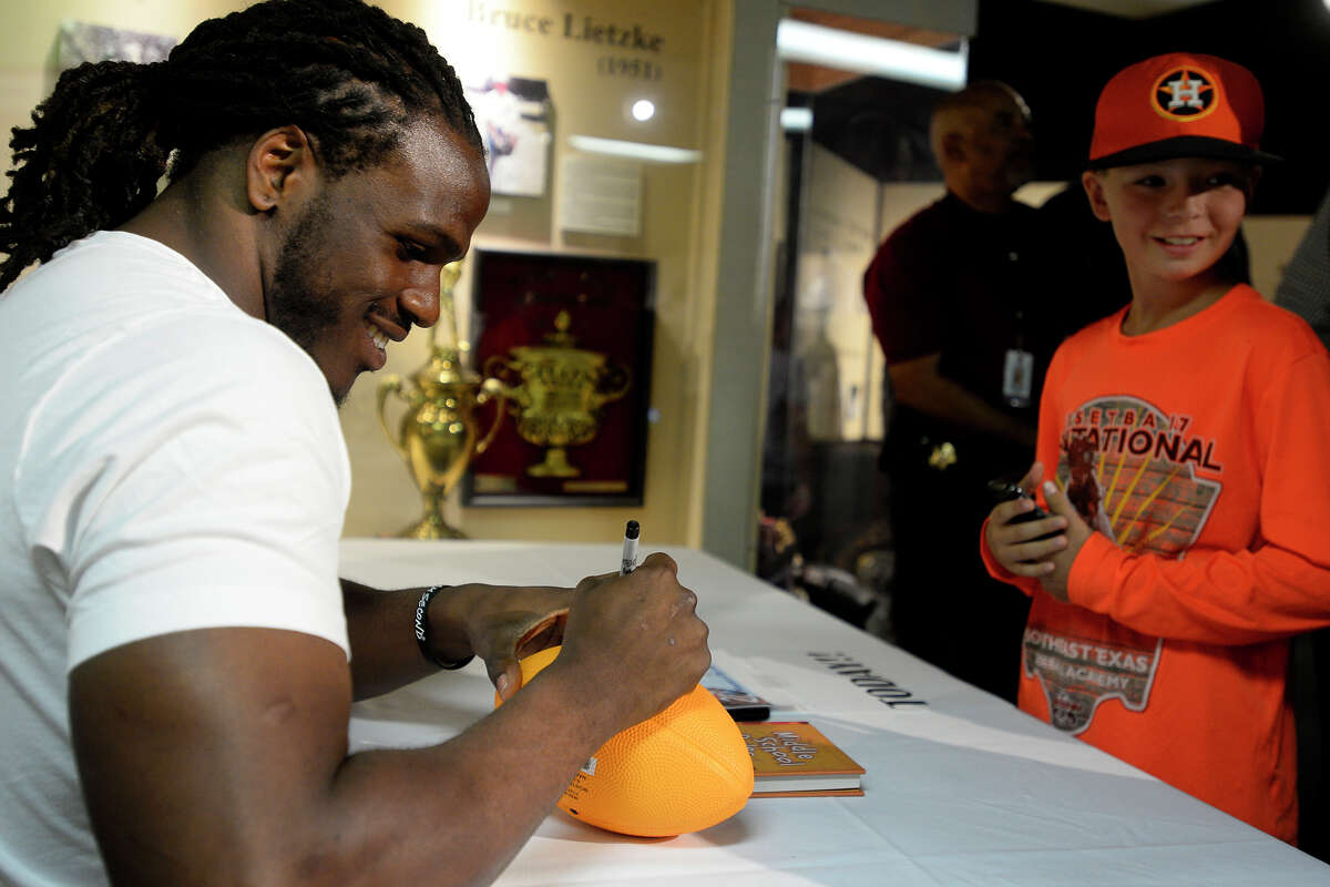 Jamaal Charles, a Port Arthur native who plays for the Denver Broncos, signs a football for Eli Curtis, 9, at the Museum of the Gulf Coast on Friday. Charles was at the museum to sign copies of his book, "The Middle School Rules of Jamaal Charles," which chronicles how he overcame his learning disability and bullying. Photo taken Friday 6/9/17 Ryan Pelham/The Enterprise