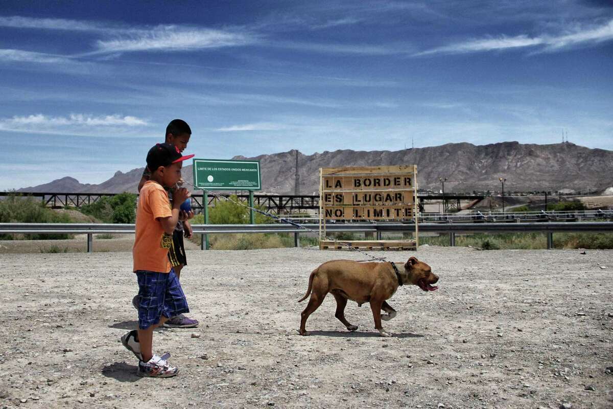 Boys walk with their dog past a wooden sign put as a project by Mexican activists known as "Letters A La Border" in Ciudad Juarez, Mexico, in the border with El Paso, in Texas, US, on May 14, 2017. / AFP PHOTO / HERIKA MARTINEZHERIKA MARTINEZ/AFP/Getty Images