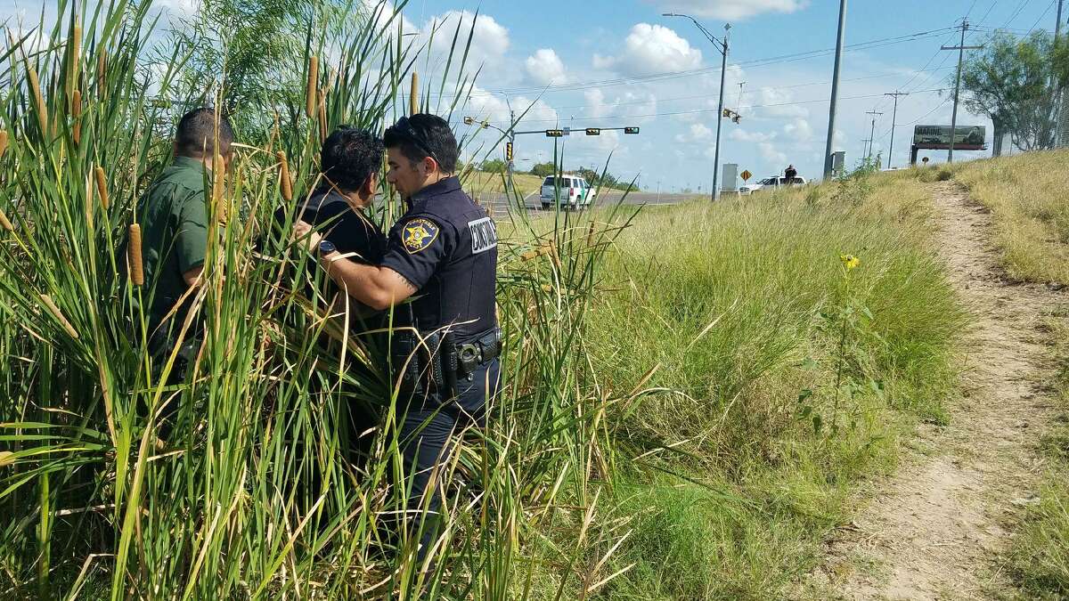 A BP agent and deputy Ricardo Rodriguez detain a man who was hiding in a brushy area by U.S. 83.