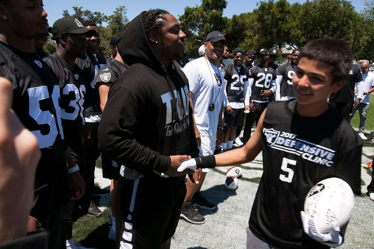 Oakland Raiders running back Marshawn Lynch congratulates Castlemont sophomore Carlos Reales (5) during a defensive drills clinic for area prep football players, Saturday, June 10, 2017, at the Raiders' headquarters in Alameda, Calif.