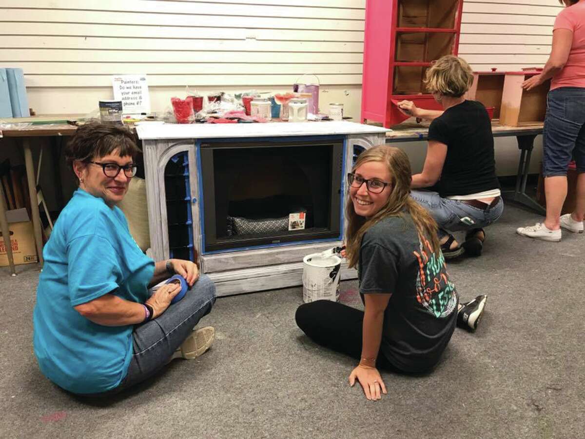Leclaire Elementary School representatives Anne Pratte and Stephanie Stacy pause from working on a project. Their group planned a special painting party at Restore Décor.