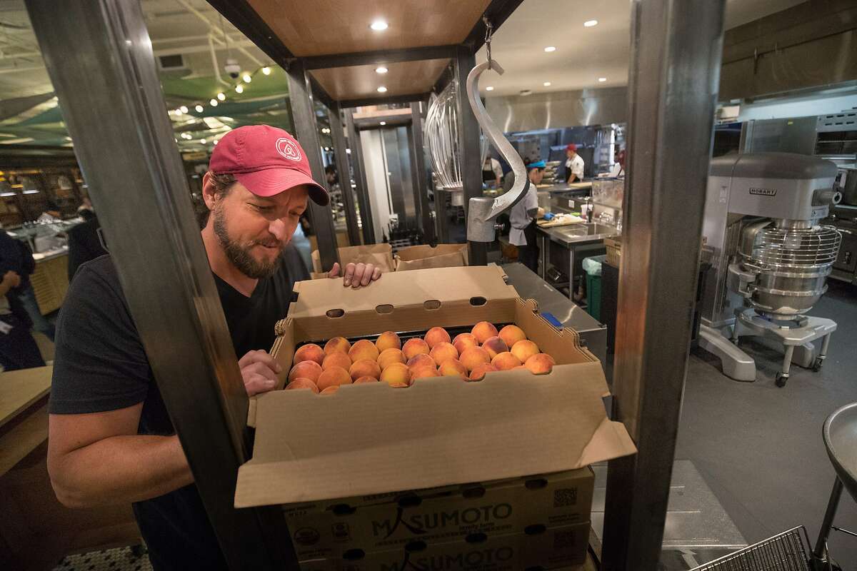 Kent Clayton, a food buyer for Airbnb, examines the Gold Dust peaches at Airbnb’s cafeteria. The peaches were picked up the day before from the Masumoto Family Farm just outside Fresno. 