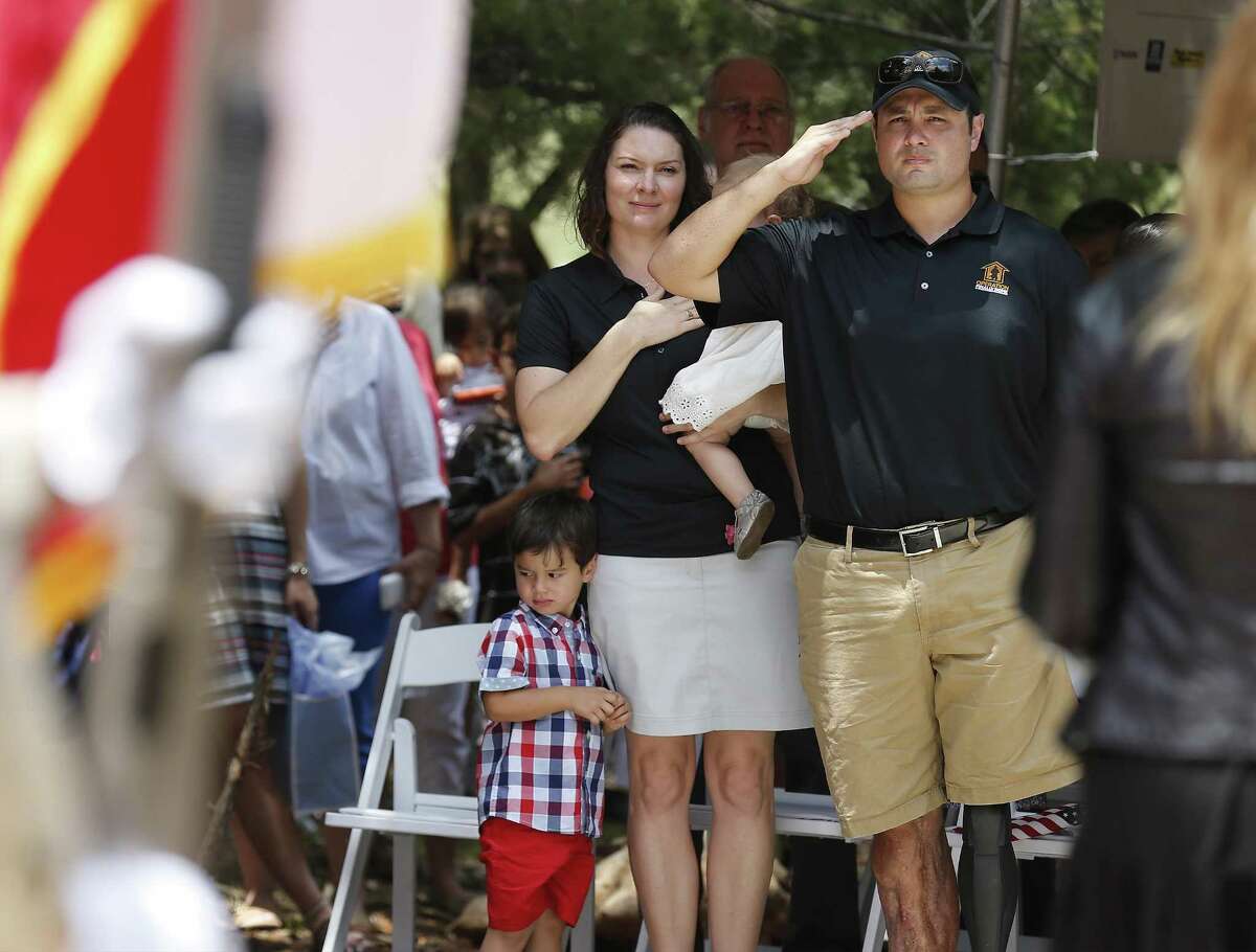 Daniel Carlton (from the right), his wife, Juanita, and their six children honor the singing of the National Anthem at the dedication of their new home Friday.