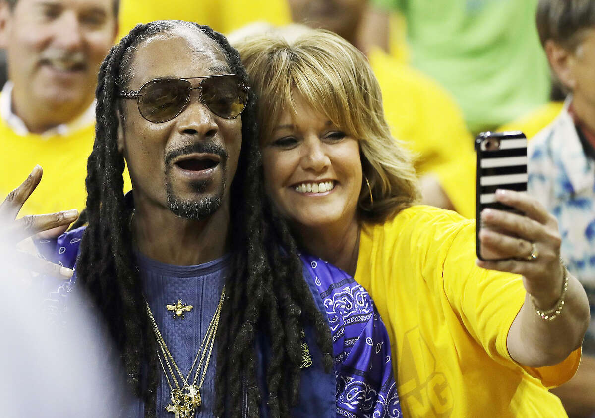 Musician Snoop Dogg, left, poses with a fan for photos before Game 5 of basketball's NBA Finals between the Golden State Warriors and the Cleveland Cavaliers in Oakland, Calif., Monday, June 12, 2017. (AP Photo/Marcio Jose Sanchez)