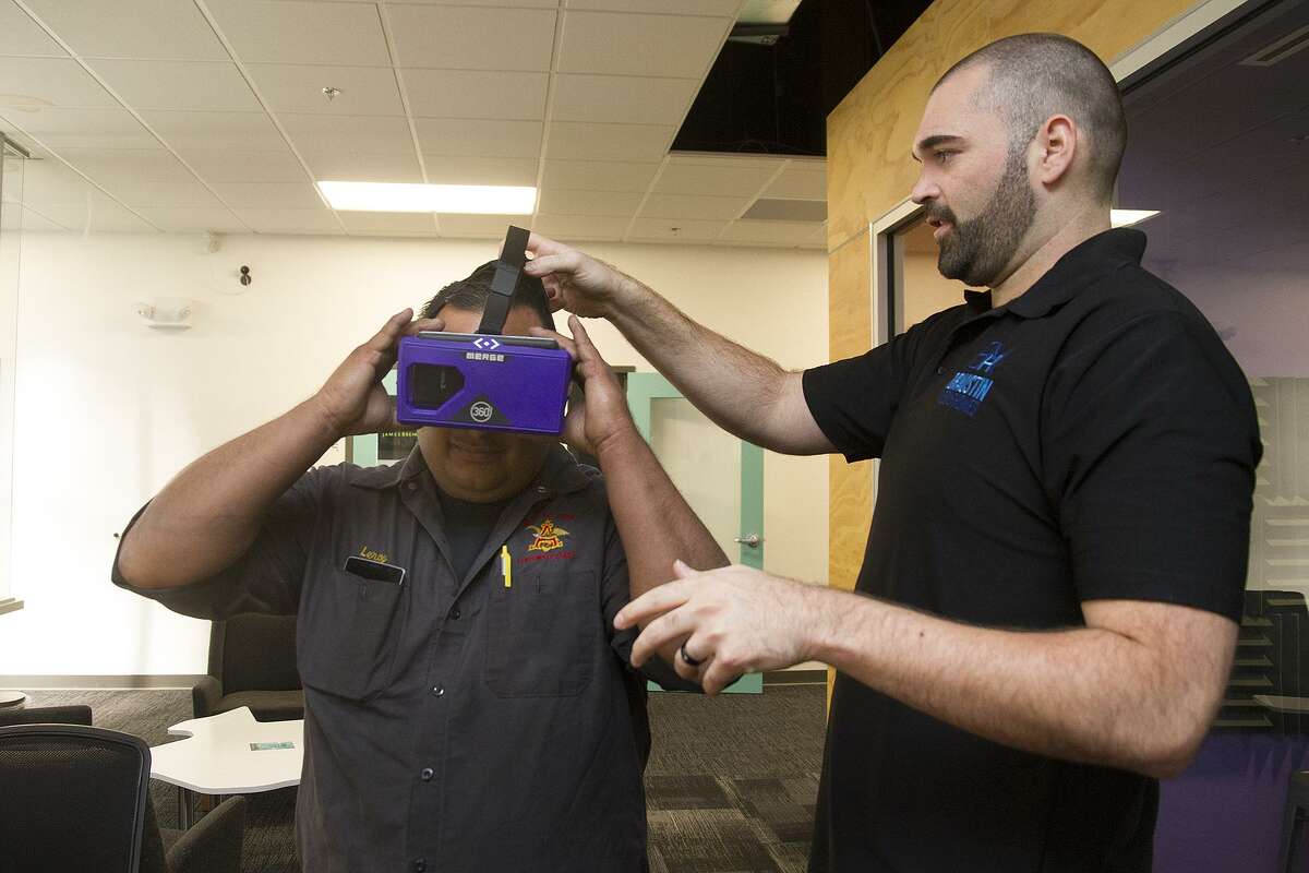 Braustin Mobile Homes President and co-founder Alberto Piña (right) helps Leroy Chavez with a pair of virtual reality goggles so Chavez can “tour” his future home. The company is based in the Geekdom office space in downtown San Antonio.