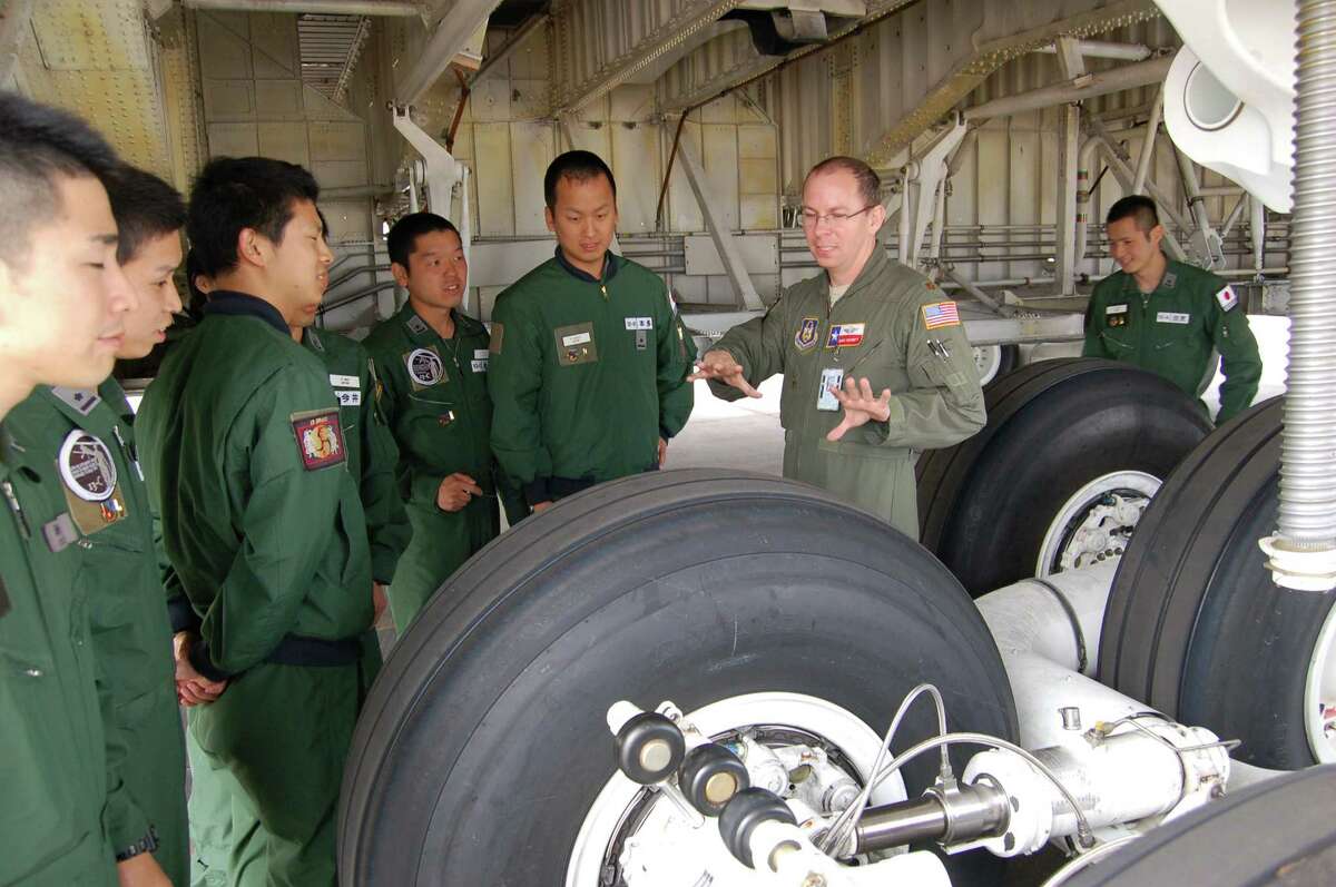 Maj. Chris Garnett, second from right, C-5A Galaxy pilot, explains the jet?’s complex landing-gear system to visiting pi'ots from the Defense Language Institute-English Language Center at Joint Base San Antonio-Lackland.