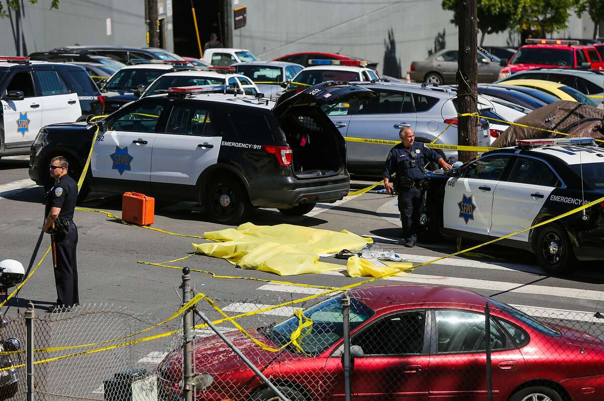 Police officers stand over a dead body at the scene of a fatal shooting at 17th Street and San Bruno Avenue in San Francisco on Wednesday, June 14, 2017.