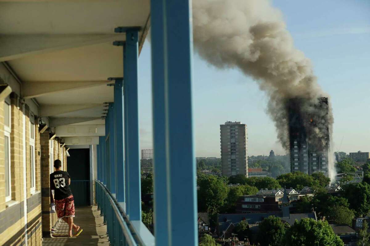 A resident of a nearby building watches the inferno engulf Grenfell Tower on Wednesday in west London. The massive fire began on the upper floors of the 24-story, high-rise apartment building.﻿