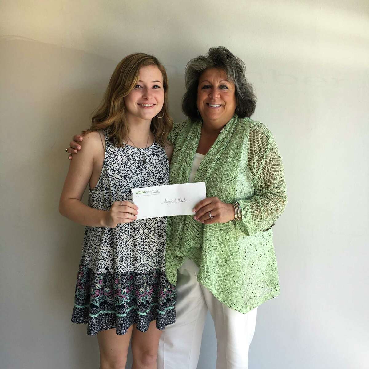 Wilton Chamber of Commerce scholarship recipient Meredith Nash holds up her award with chamber vice president, Carol Johnson.