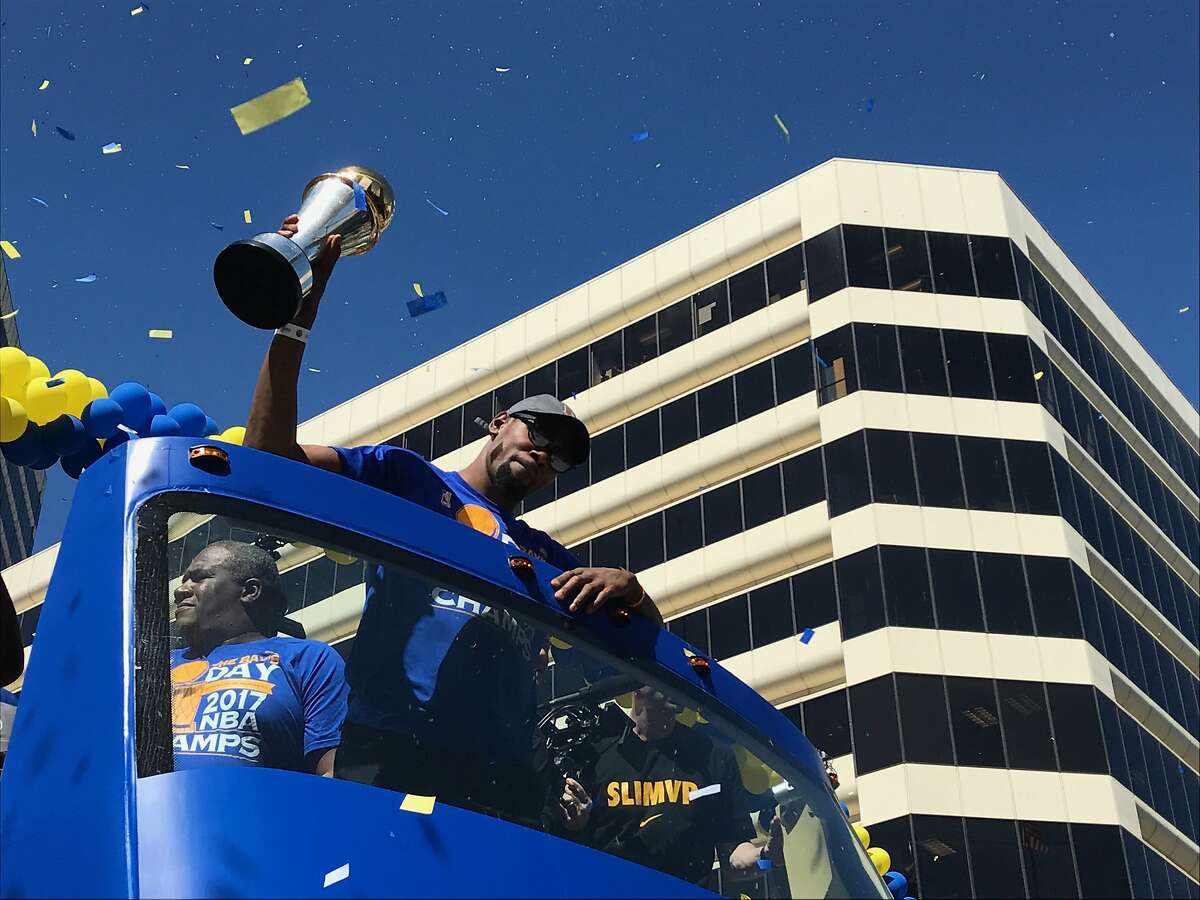 Kevin Durant holds up the NBA MVP trophy in downtown Oakland, Calif. as thousands of fans watch the Warriors Championship Parade on Thursday, June 15, 2017.