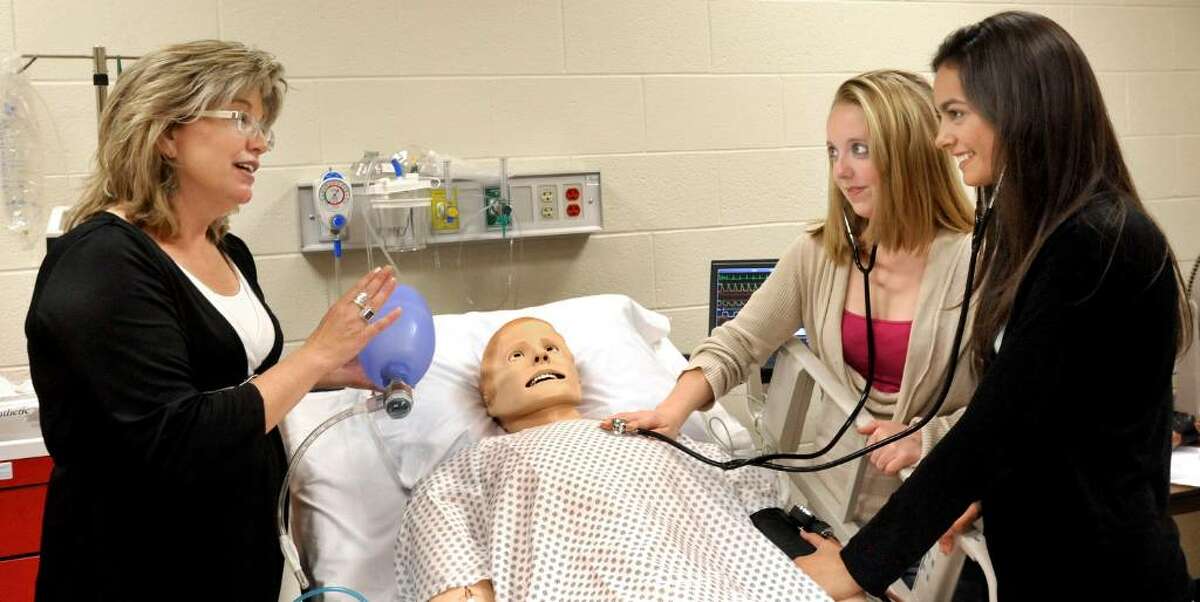 Colleen Cox, technical specialist for the nursing department, left, explains the human simulator to incomming nursing students Elizabeth Irwin, of New Fairfield, right center, and Alexis Folz, of Ridgefield, right, both 17, in the ICU simulation lab at WCSU on Tuesday, June 8, 2010.