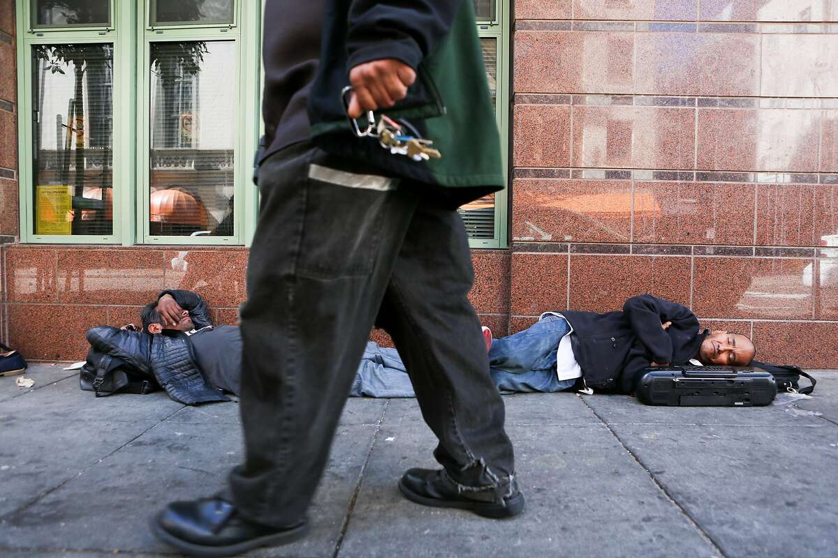 A man walks past two homeless men sleeping on the sidewalk on Ellis Street, an area known for it's chronic homeless encampments on Thursday, June 15, 2017 in San Francisco, Calif.
