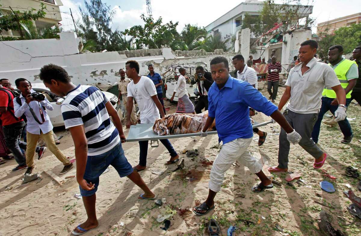 Men carry away the body of a civilian who was killed in a militant attack that began Wednesday night at a popular pizza restaurant in Mogadishu, Somalia.﻿