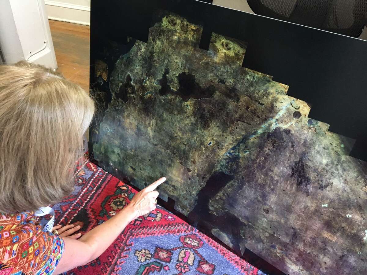 Alamo Conservator Pam Rosser points to an ultraviolet photo mosaic of the south wall of the sacristy of the historic Alamo church. The wall is believed to have had a decorative horizontal band, or frieze, running across it, during the 1700s, as well as a similar ornamentation parallel to the wall's arch-shaped top.