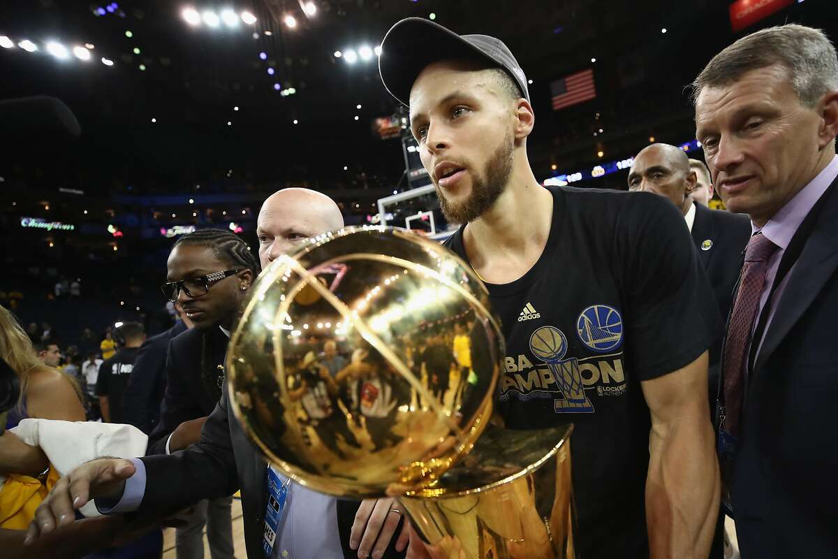 Stephen Curry #30 of the Golden State Warriors carries off the Larry O'Brien Championship Trophy after defeating the Cleveland Cavaliers 129-120 in Game 5 to win the 2017 NBA Finals at ORACLE Arena on June 12, 2017 in Oakland, California.