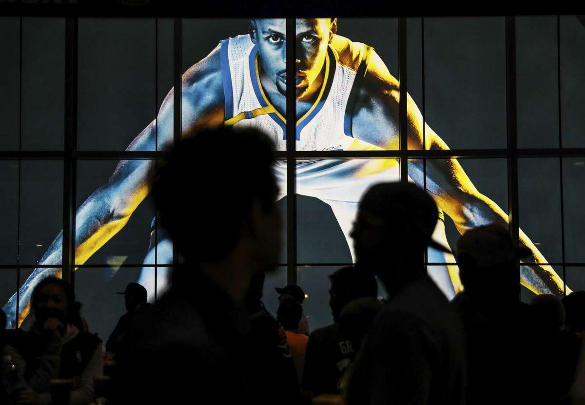 Warriors fans walk past an image of Stephen Curry at Oracle Arena.