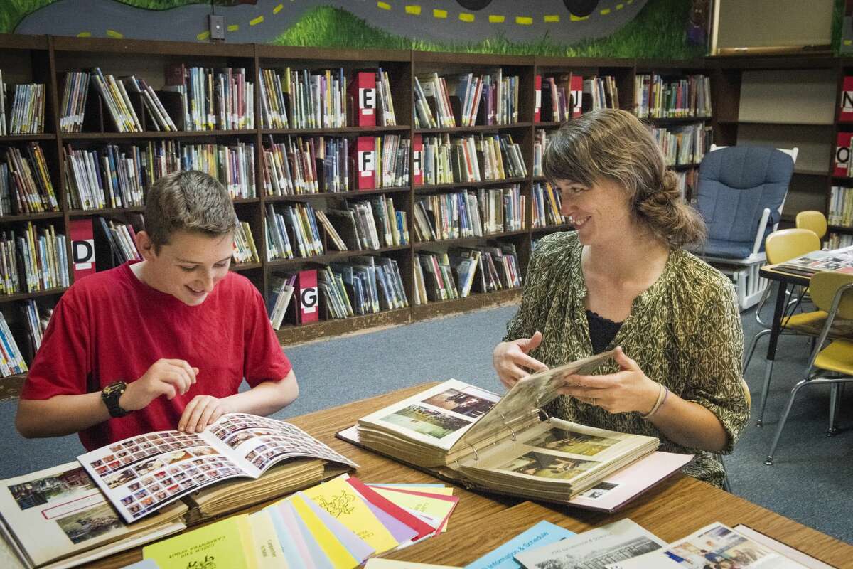 DANIELLE McGREW TENBUSCH | for the Daily News Gavin Gilmore, 13, and his mother Kellie Gilmore laugh as they look through old photo albums during an open house and farewell party at Carpenter Street Elementary School in Midland. "I'm sad, but on to bigger and better things," Kellie Gilmore said, referencing the new Central Park Elementary School, which will open for the 2017-18 school year. Carpenter Street and Eastlawn elementary schools will be combined into the STEM-focused school.