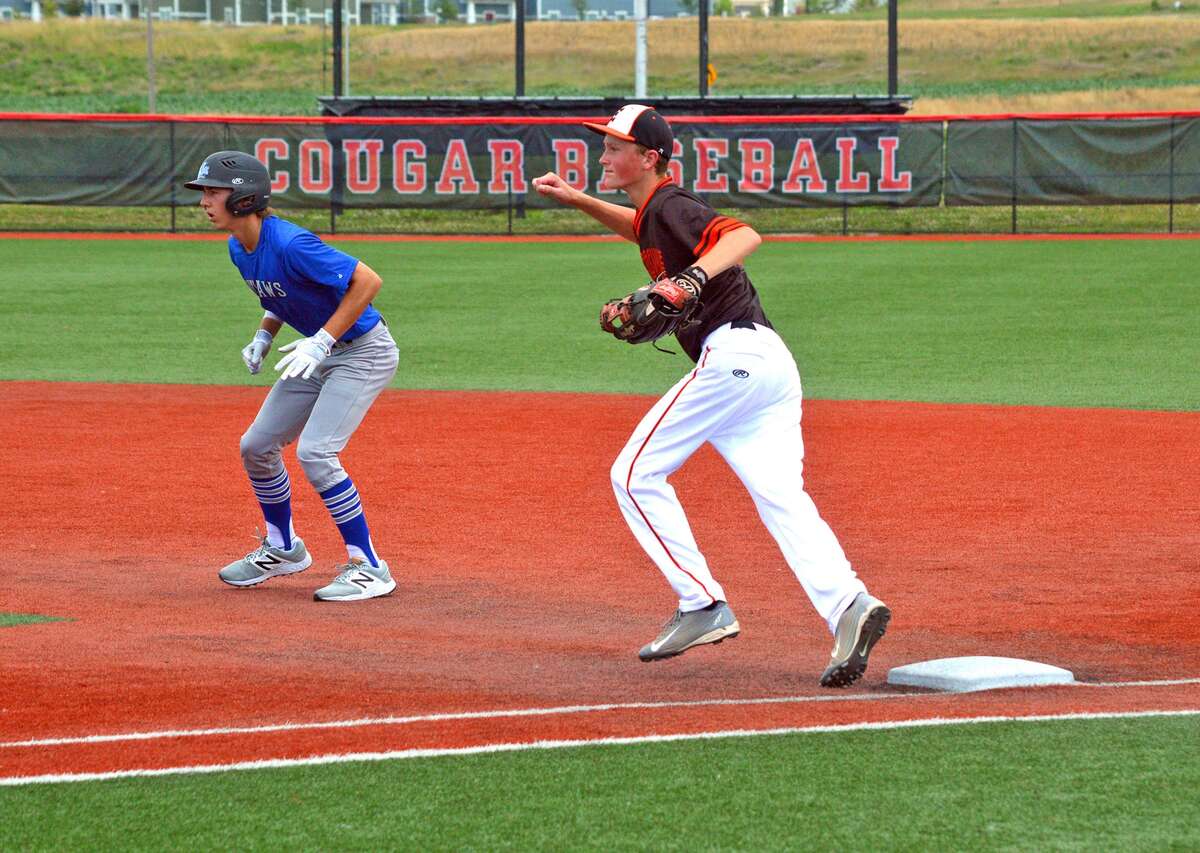 Edwardsville first baseman Zac Crutchfield, right, holds an Illinois Central Outlaws runner on base during the seventh inning of Friday’s game at SIUE.