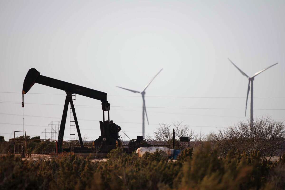 An oil well pumps oil as wind turbines produce energy in Fort Stockton. ( Michael Paulsen / Houston Chronicle )