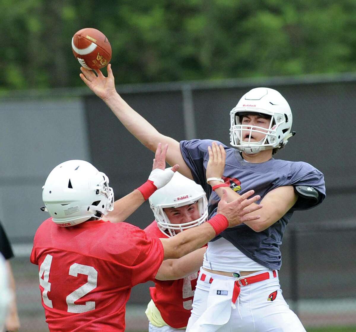 White quarterback Gavin Muir, right, just gets off a pass as he is pressured by two red players including Gramoz Bici (42) during the annual Greenwich High School Red vs. White spring scrimmage at Cardinal Stadium, Greenwich, Conn., Saturday, June 17, 2017.