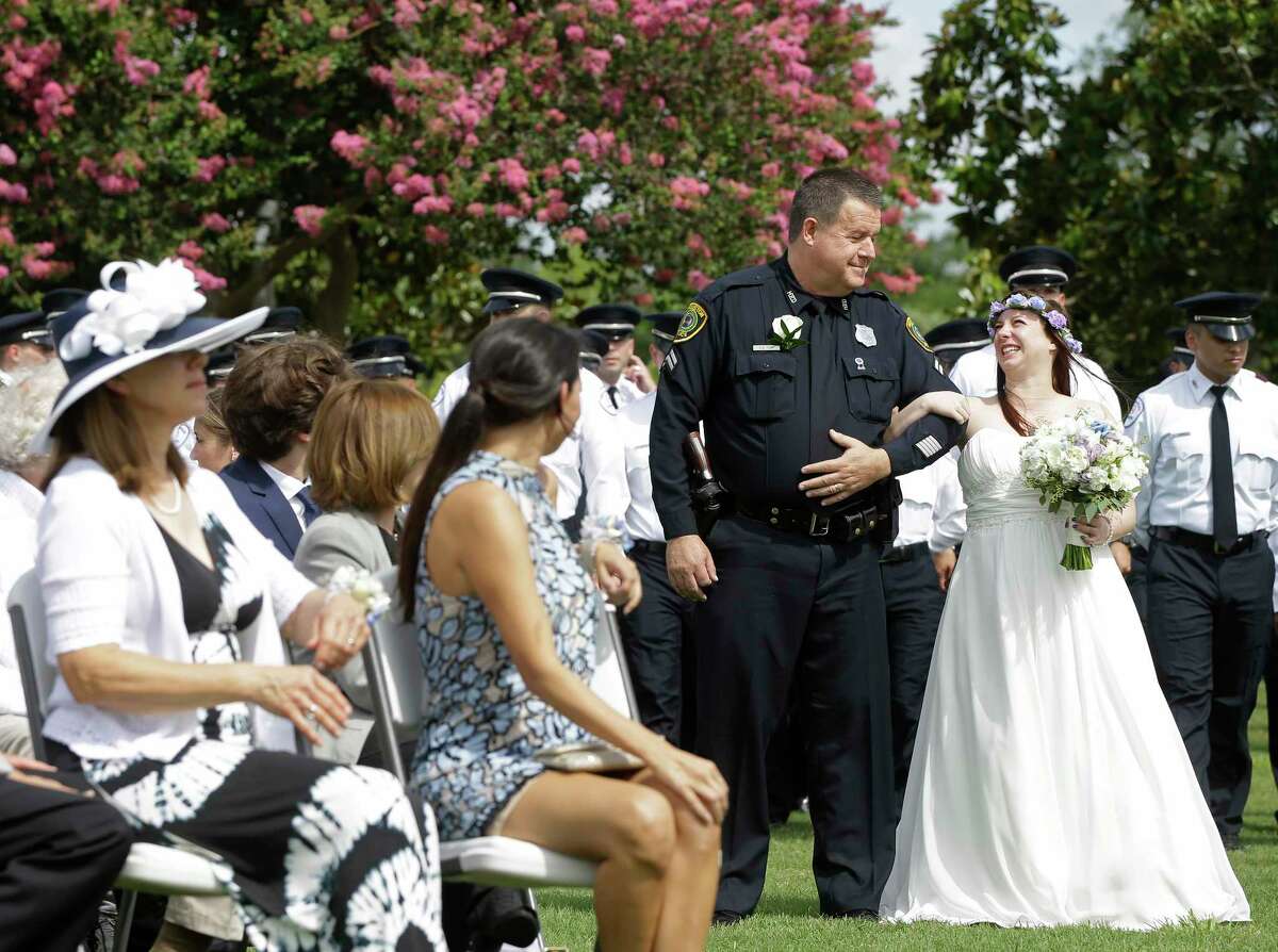 Ray Hunt, Houston Police Officers' Union president, escorts Cynthia Martin during her wedding at the Houston Police Officer Memorial.﻿
