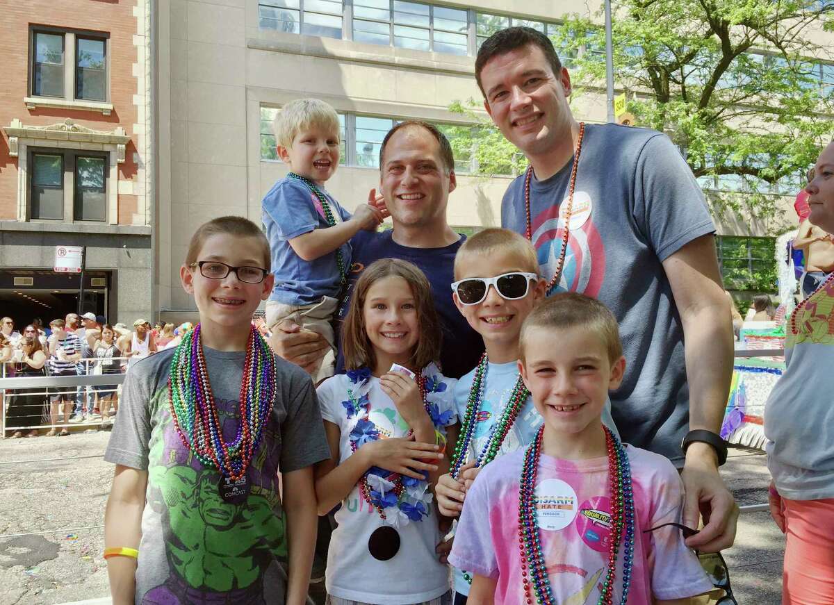This June 26, 2016 photo provided by the family shows Kevin Neubert, background center, and Jim Gorey with their adopted children, from left, Luke, Derek, Natalie, Zach, and Jacob at the Chicago Pride Parade. Following night classes to qualify as foster parents, Neubert and Gorey agreed in December 2011 to provide a temporary home for a newborn baby. A stay intended to last only for a few days was extended into several months, and Neubert and Gorey learned that the baby had four older siblings who were also in foster care. They eventually decided to adopt all five. (Nicole Gifford Baugh/Jim Gorey via AP)
