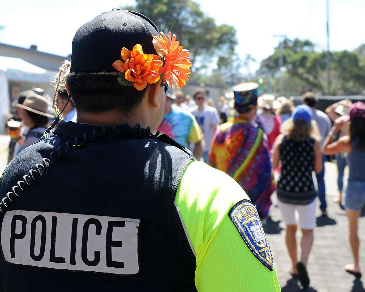 Adorning his hat with orange flowers, Monterey police officer Lidio Soriano walks through the grounds at the Monterey International Pop Festival Celebrates 50 Years at the Monterey County Fairgrounds in Monterey, Calif. on June 17, 2017.