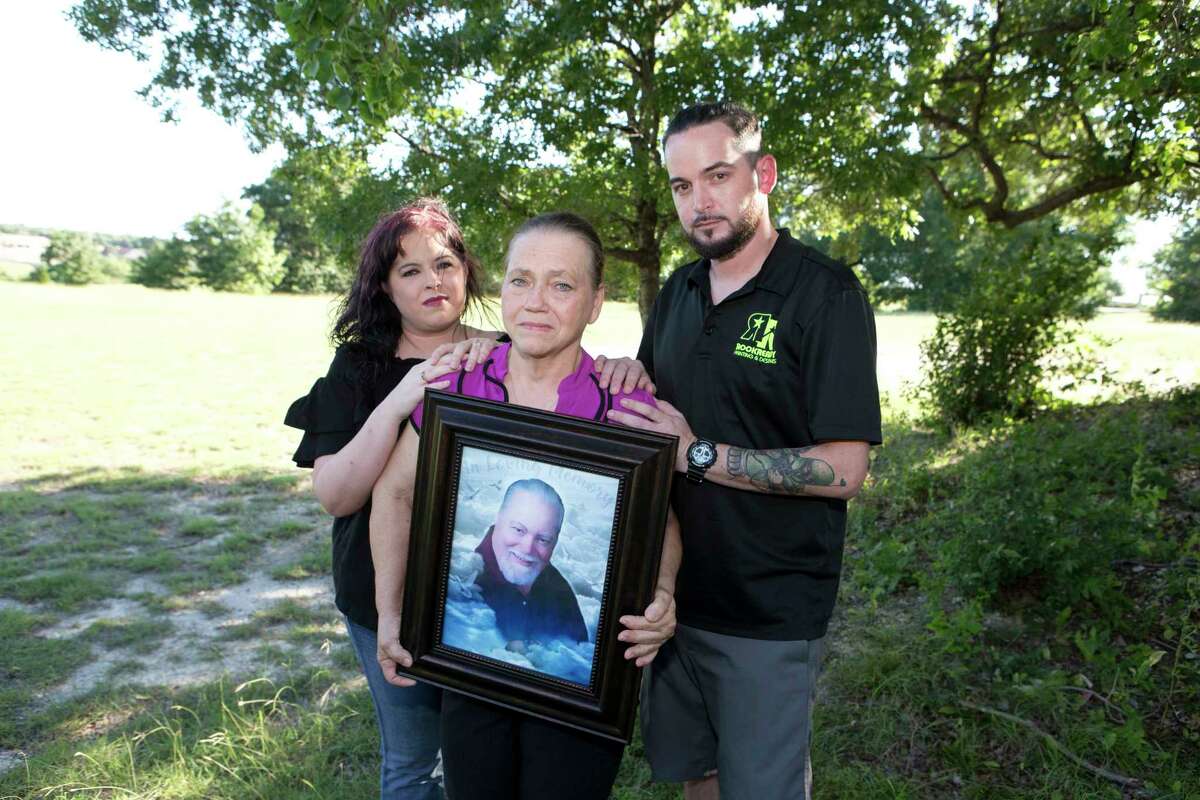 Sandra McCollum, center, ﻿holds a portrait of her late husband Larry McCollum with his children.﻿