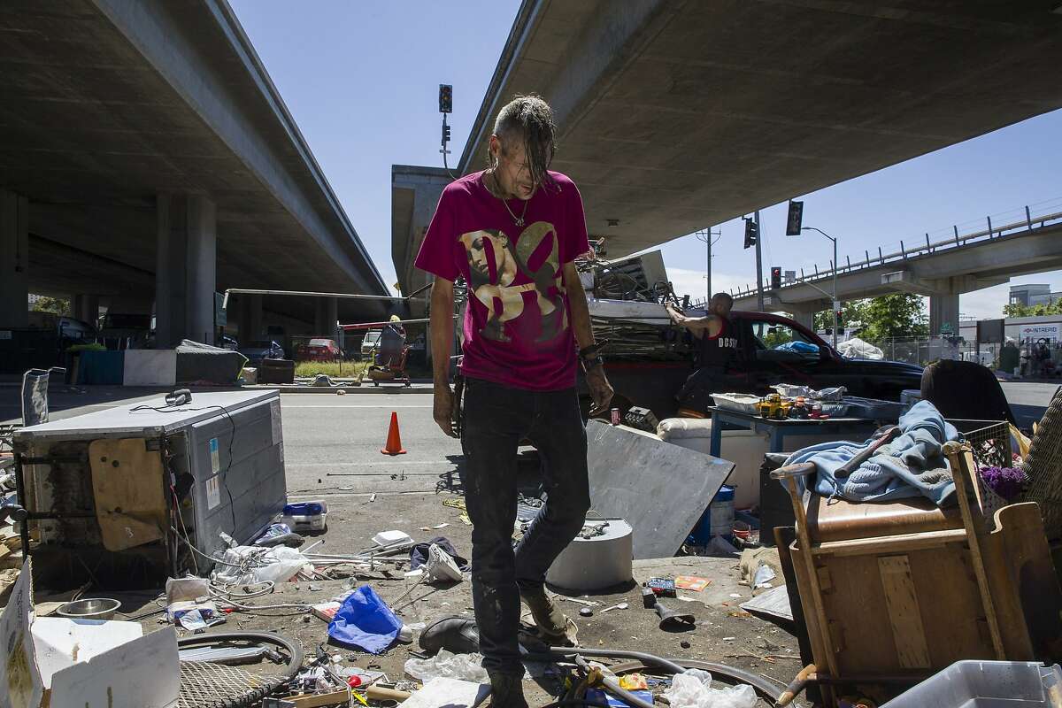 Andrew Haid checks for scrap metal to fill the truck outside his camp at 5th and Market Street on Friday, June 9, 2017, in Oakland, Calif.