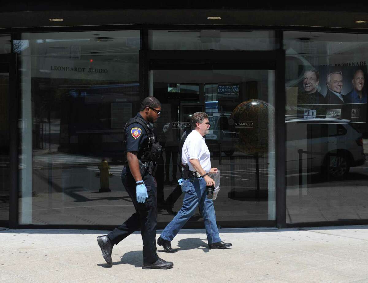 Accompanied by a police officer, Crime Scene Investigator Ed Rondano, right, carries an evidence bag of fecal matter from the scene where a Swastika written in fecal matter was found on the windows of Rich Forum in Stamford, Conn. Monday, June 18, 2017.