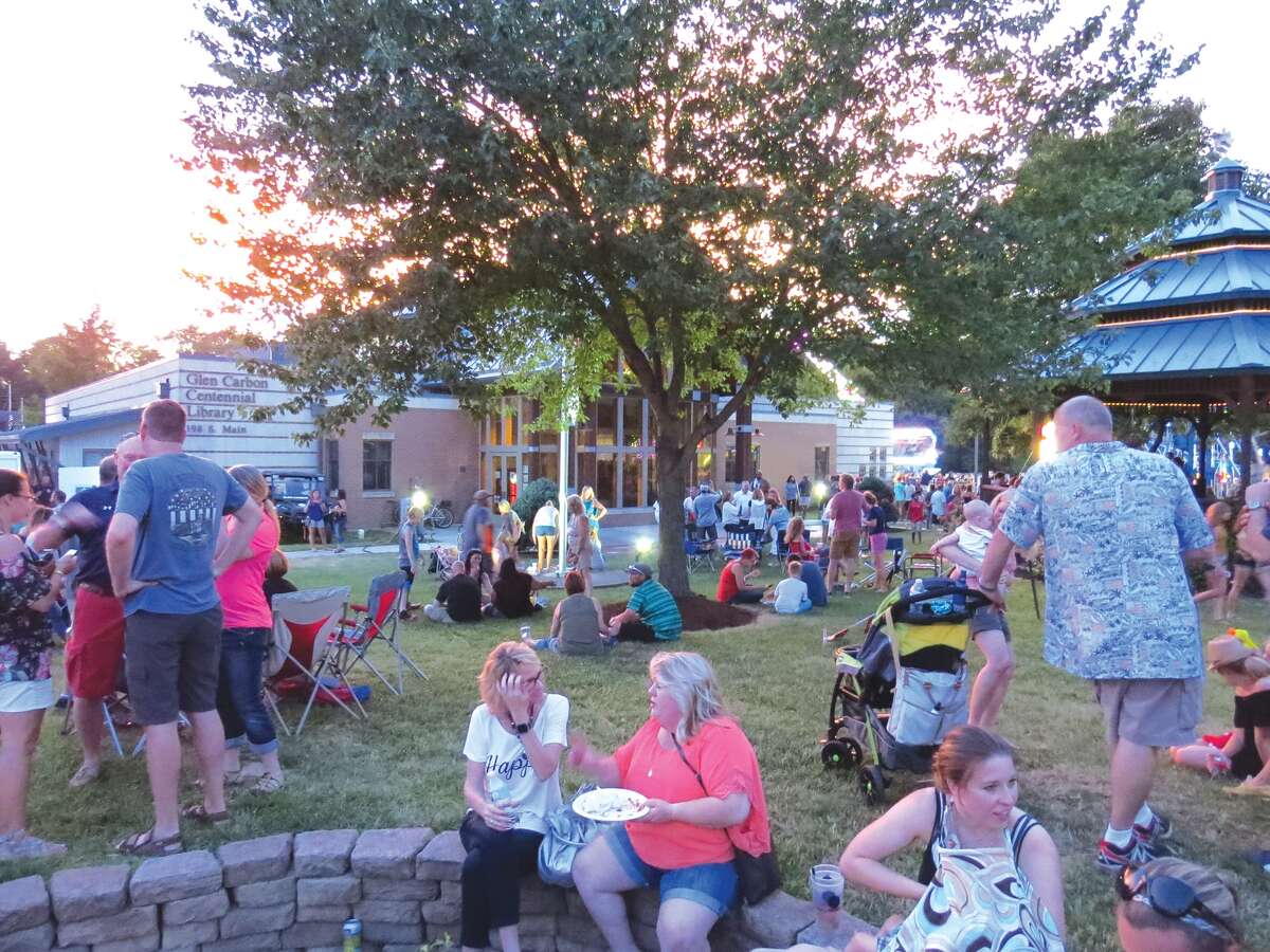 Visitors to the Glen Carbon Homecoming take a break on the lawn in front of the Centennial Library Saturday night. The event featured live music, carnival rides, a parade, fireworks and plenty of food and drinks.