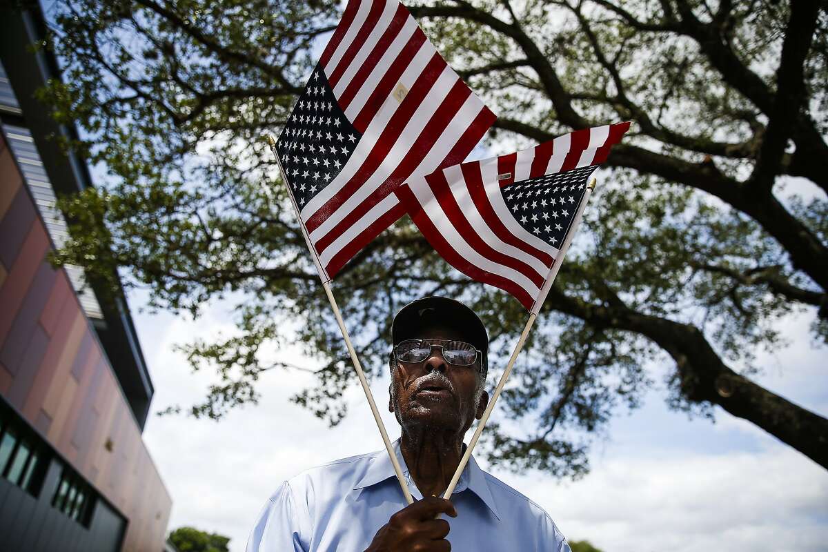 John Tayor, a resident of the Third Ward since 1957, holds american flags in a "V for victory" as he walks around Emancipation Park during the rededication ceremony for the space after it underwent a $33 million renovation Saturday, June 17, 2017 in Houston. ( Michael Ciaglo / Houston Chronicle )