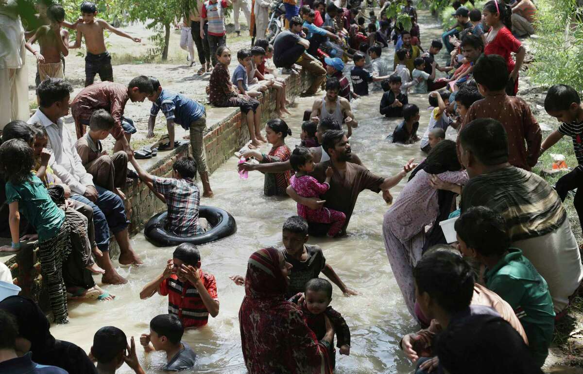 Pakistan families cool themselves off in a water stream in Lahore, Pakistan. Killer heat is getting worse, a new study shows.