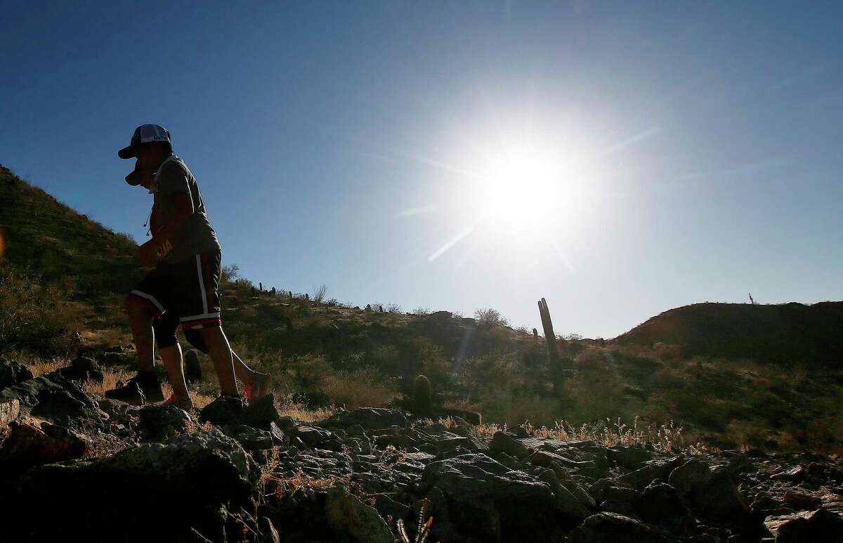 FILE - In this June 15, 2017 file photo, hikers brave the afternoon sun as the temperatures hit 110-degrees in Phoenix. Killer heat is getting worse, a new study shows. Deadly heat waves like the one now broiling the American West are bigger killers than previously thought and they are going to grow more frequent, according to a new comprehensive study of fatal heat conditions. Still, those stretches may be less lethal in the future, as people become accustomed to them. (AP Photo/Ross D. Franklin, File)