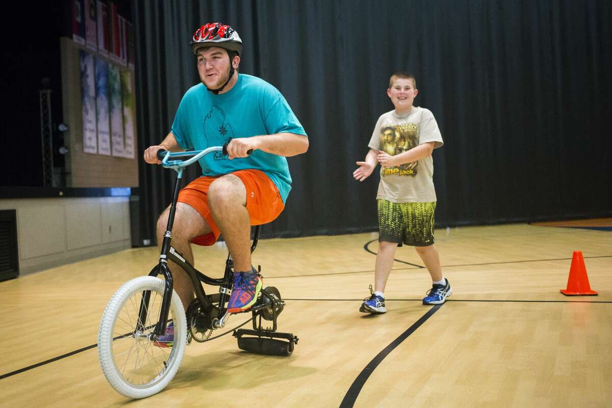 Russell Pitt of Midland, left, rides a modified bike around a track as Adam Jammer of Midland, 12, right, follows behind him during the iCan Bike Camp hosted by The Arc of Midland on Monday, June 19, 2017 at Midland Evangelical Free Church. The iCan Bike roller equipment was designed to help youths with disabilities learn how to ride a bike. The camp continues through Friday, June 23, 2017.