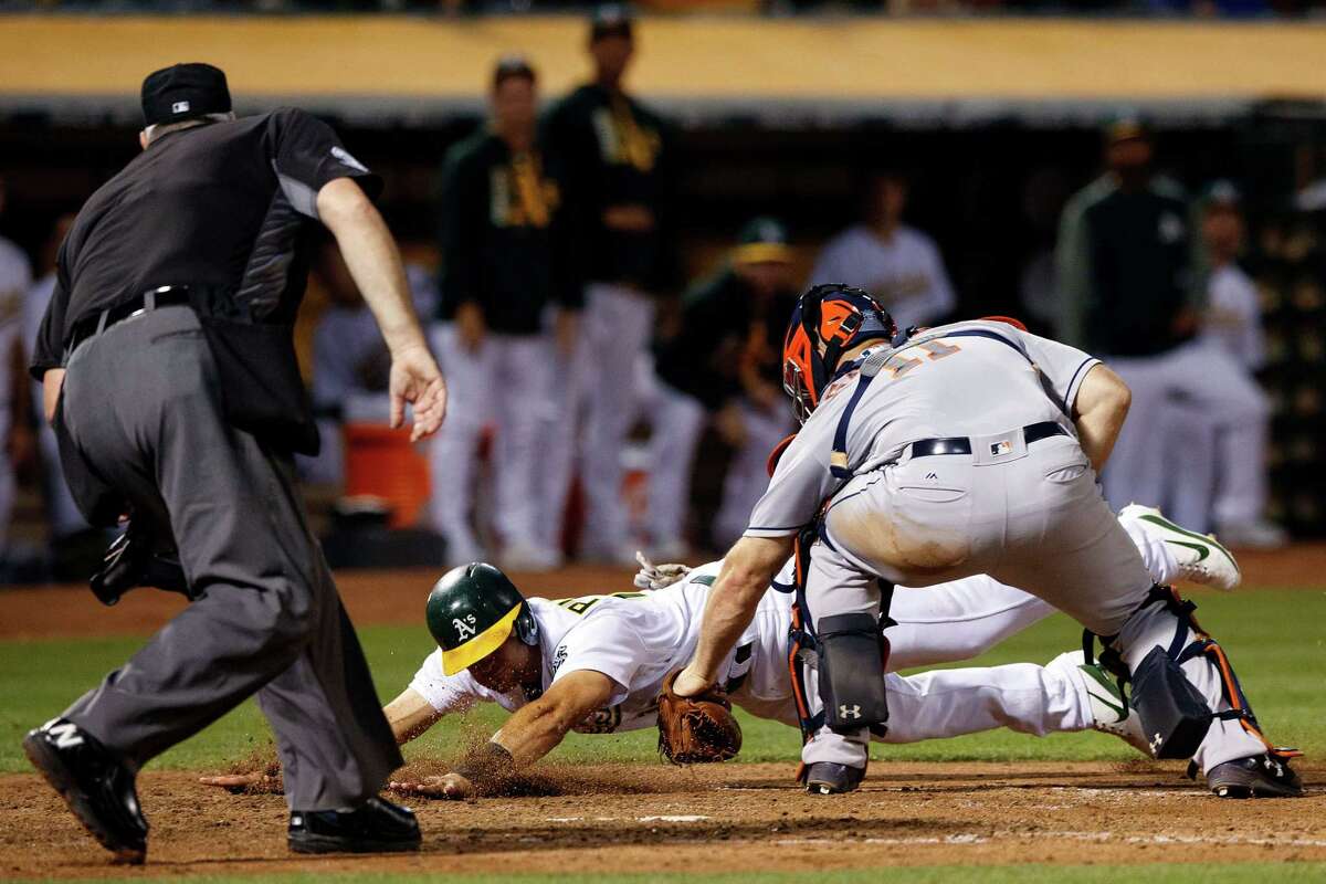 OAKLAND, CA - JUNE 19: Chad Pinder #18 of the Oakland Athletics is tagged out at home plate by Evan Gattis #11 of the Houston Astros in front of umpire Tim Welke #3 during the sixth inning at the Oakland Coliseum on June 19, 2017 in Oakland, California. The Houston Astros defeated the Oakland Athletics 4-1.